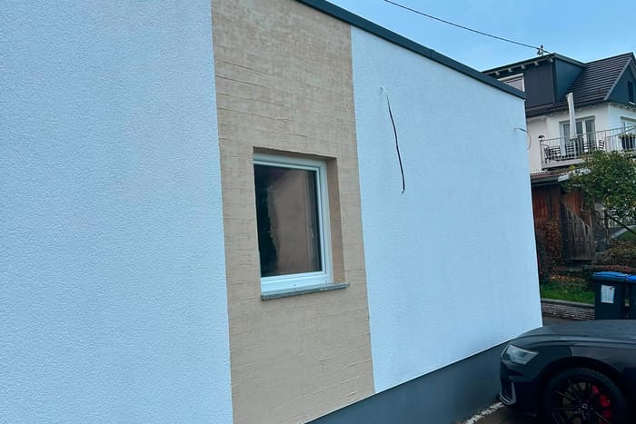Instand gesetzte helle Putzfassade mit Fenster an einem Wohnhaus